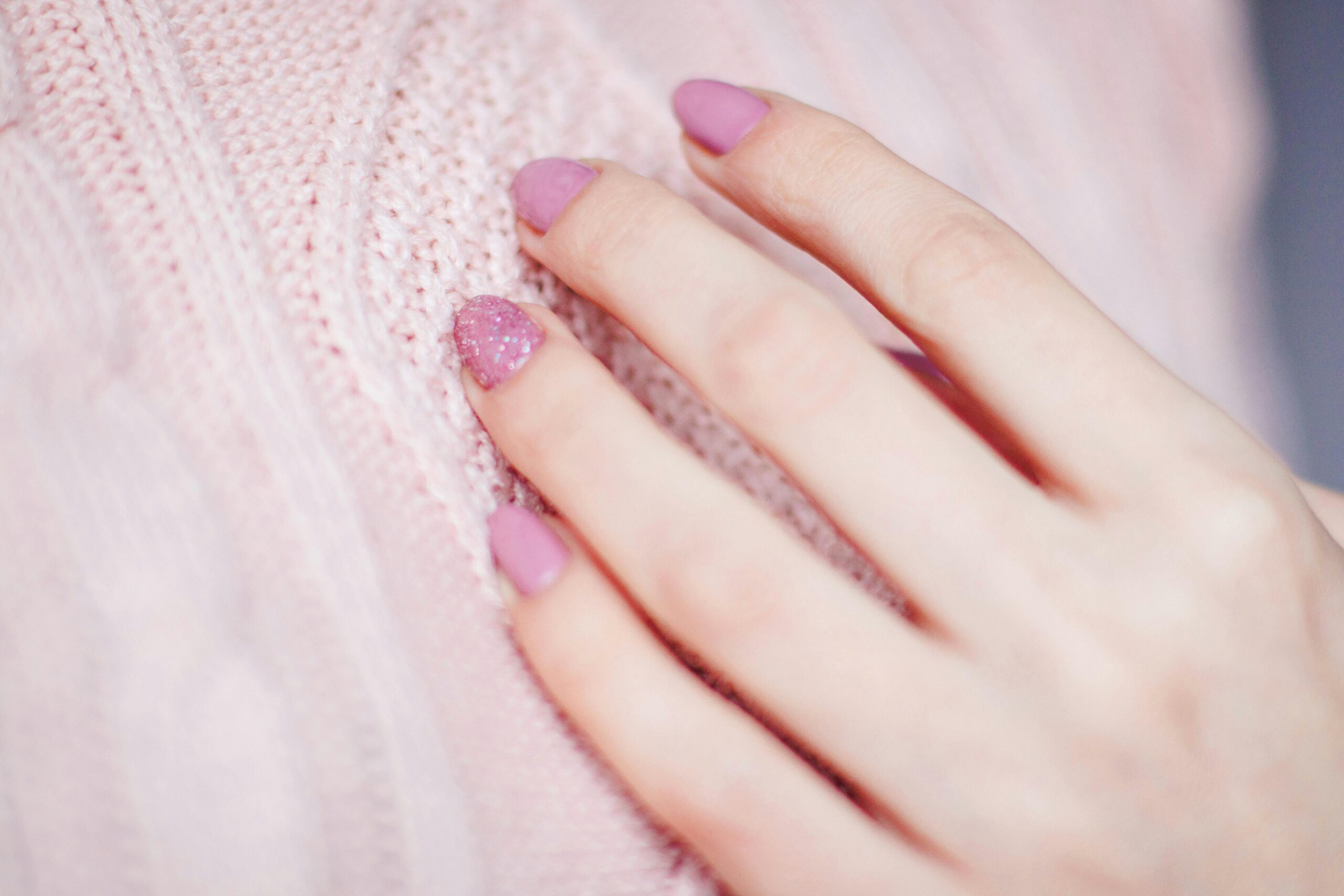 pexels-photo-939834-939834 Close-up of a woman's hand with pink manicure resting on a soft knit sweater, showcasing elegance and fashion.